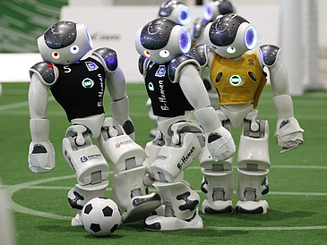 Drei Roboter spielen Fu?ball.